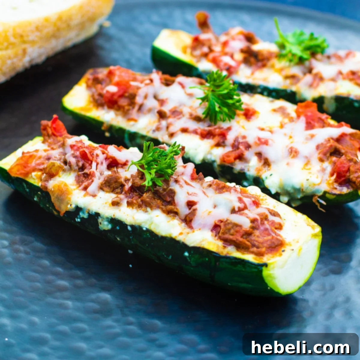 Three baked Lasagna Zucchini Boats presented on an elegant white serving platter, ready to be enjoyed.