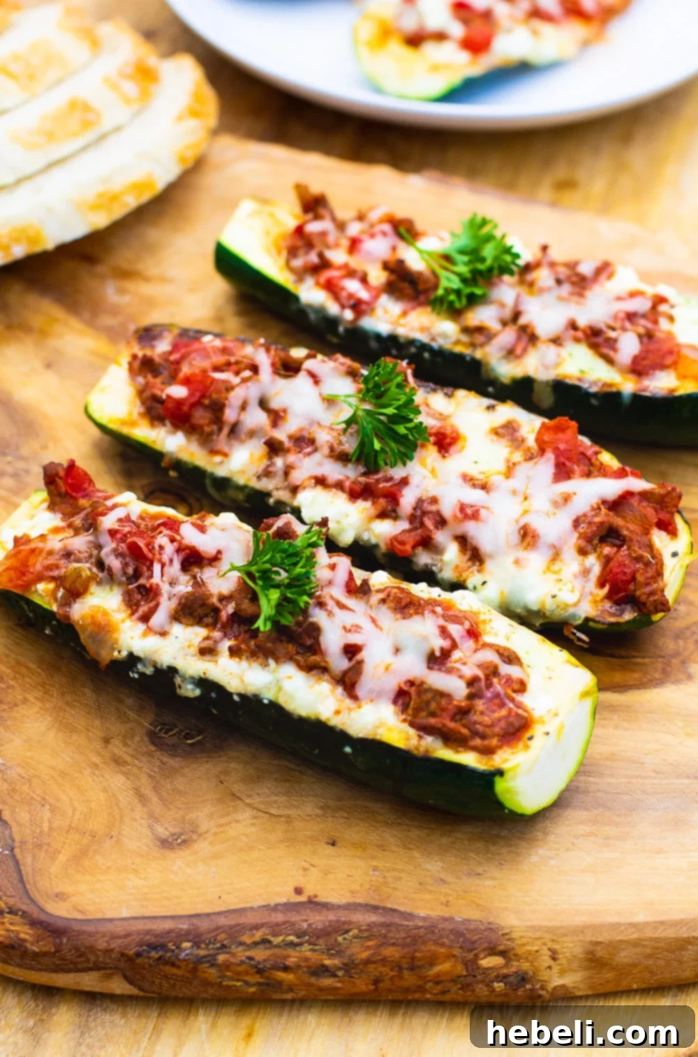 Close-up shot of two Lasagna Zucchini Boats, generously topped with melted cheese and fresh basil, ready to be served.