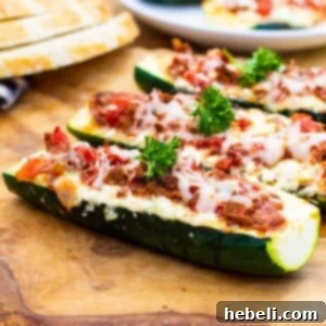 Three Lasagna Zucchini Boats on a wood cutting board, showcasing the delicious meal.