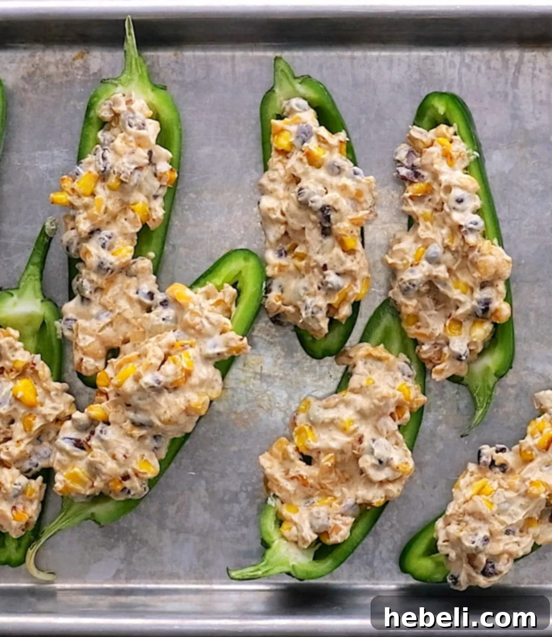 Fiesta Black Bean and Corn Jalapenos 4 Jalapenos stuffed with creamy black bean and corn mixture, ready for baking.