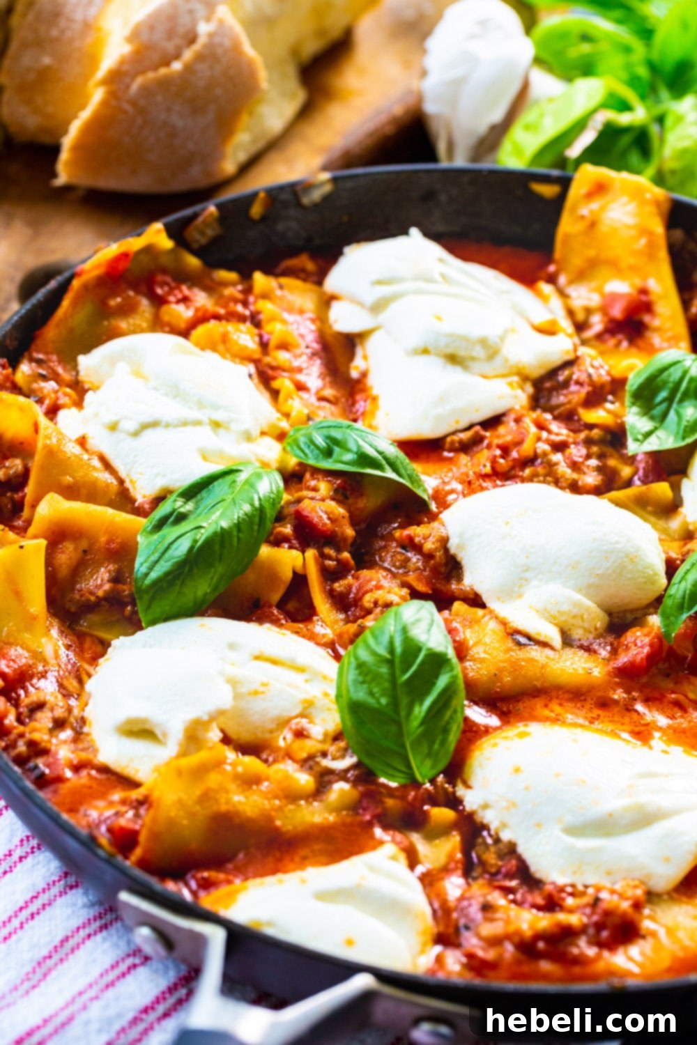 Easy Skillet Lasagna in a large pan, garnished with fresh basil, ready to serve with bread.
