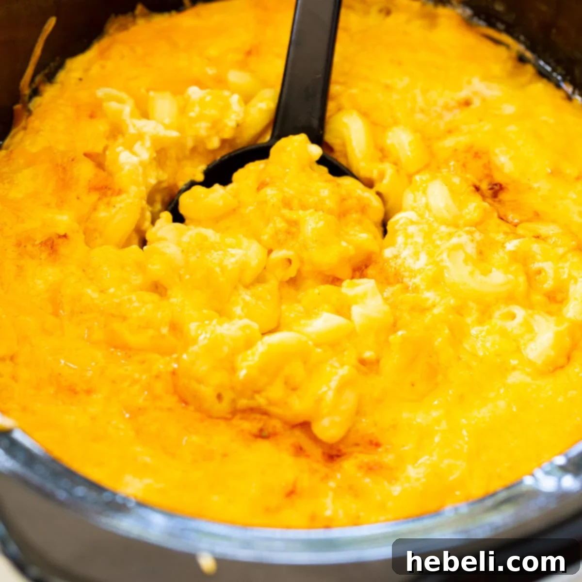 A spoon scooping a generous portion of Trisha Yearwood's rich and creamy Slow Cooker Mac and Cheese directly from the crockpot.
