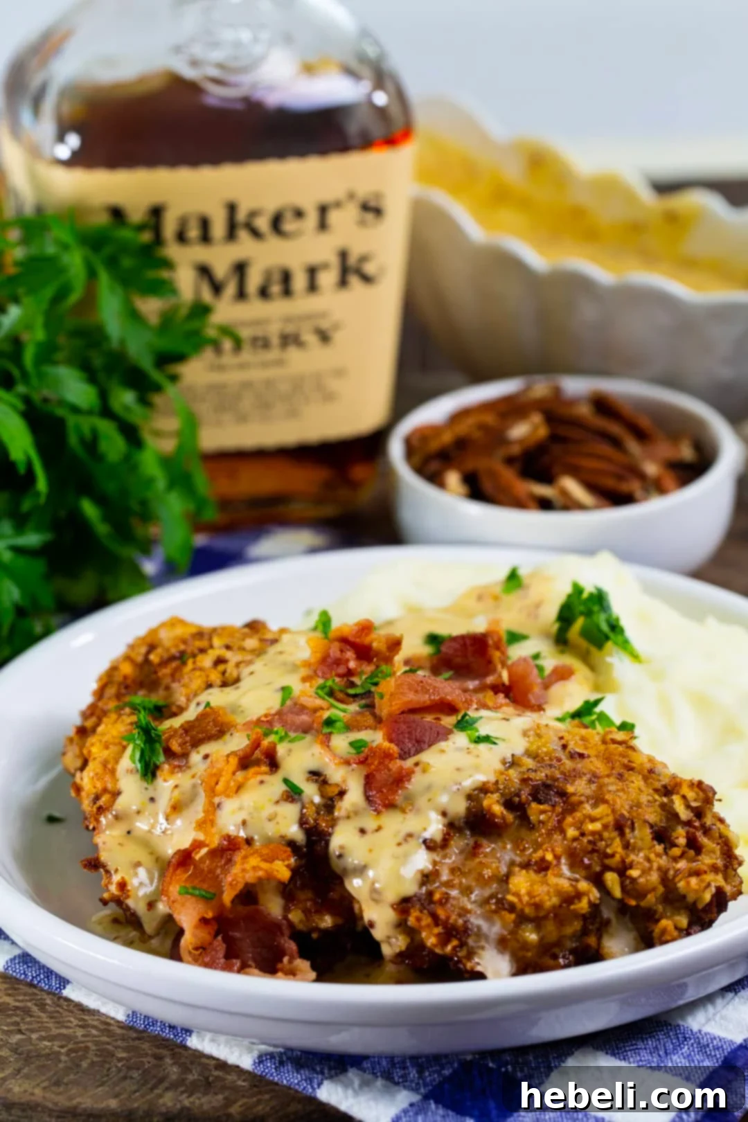Finished pecan chicken dish on a plate and a bottle of bourbon in the background.