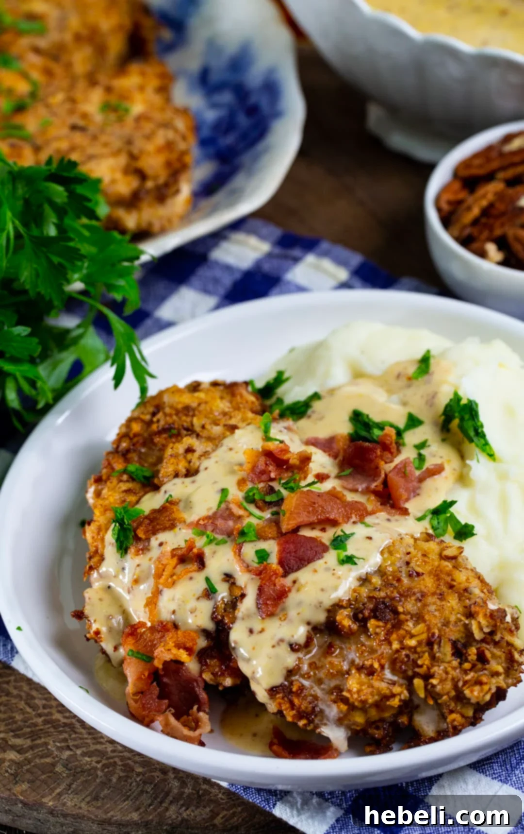 Pecan Chicken in Bourbon Maple Cream Gravy on a plate with mashed potatoes and chives.