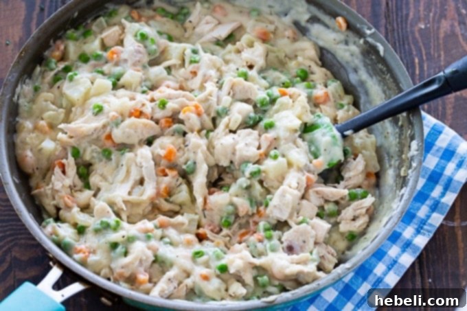 Creamy chicken pot pie filling simmering in a skillet