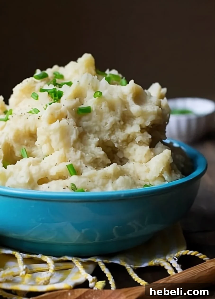 A vibrant blue serving bowl filled with creamy Crockpot Mashed Potatoes, garnished with fresh herbs, ready to be served at a holiday feast.