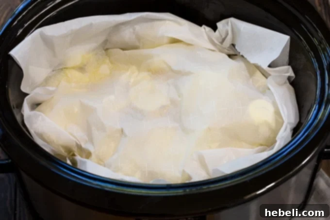 A close-up of tender, cooked potatoes being mashed directly in the slow cooker, showing the creamy texture of the Crock Pot Mashed Potatoes.