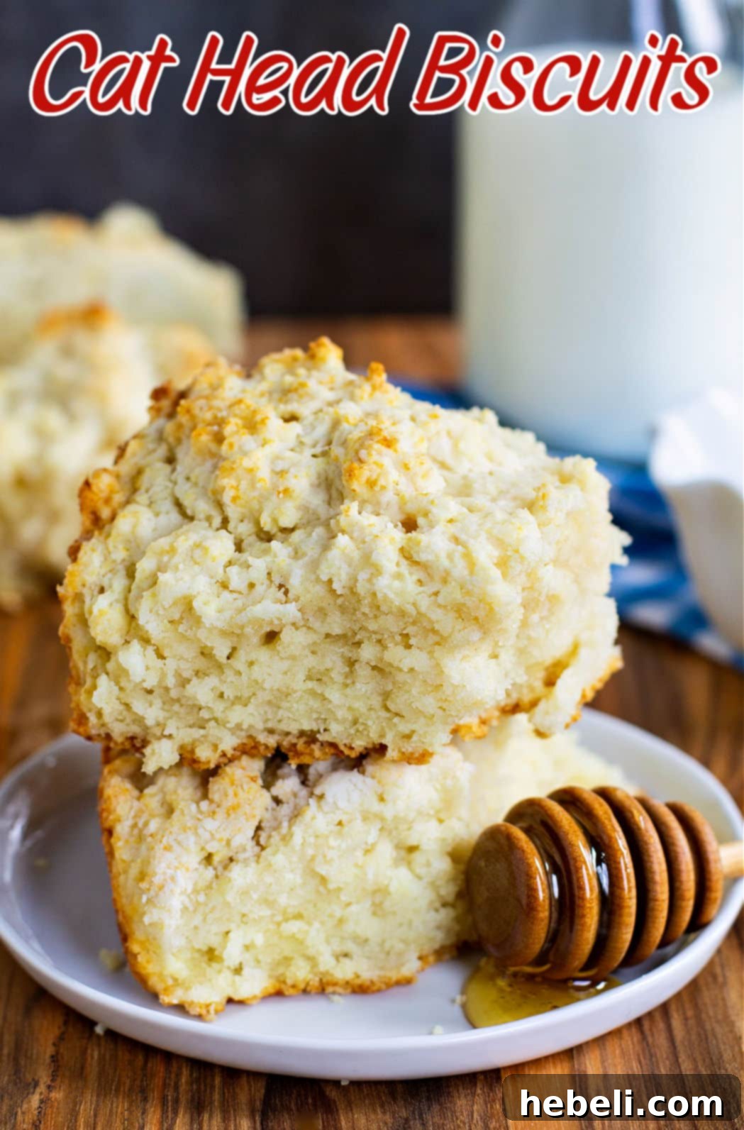 Two Cat Head Biscuits, one atop the other, on a textured surface, highlighting their substantial size.