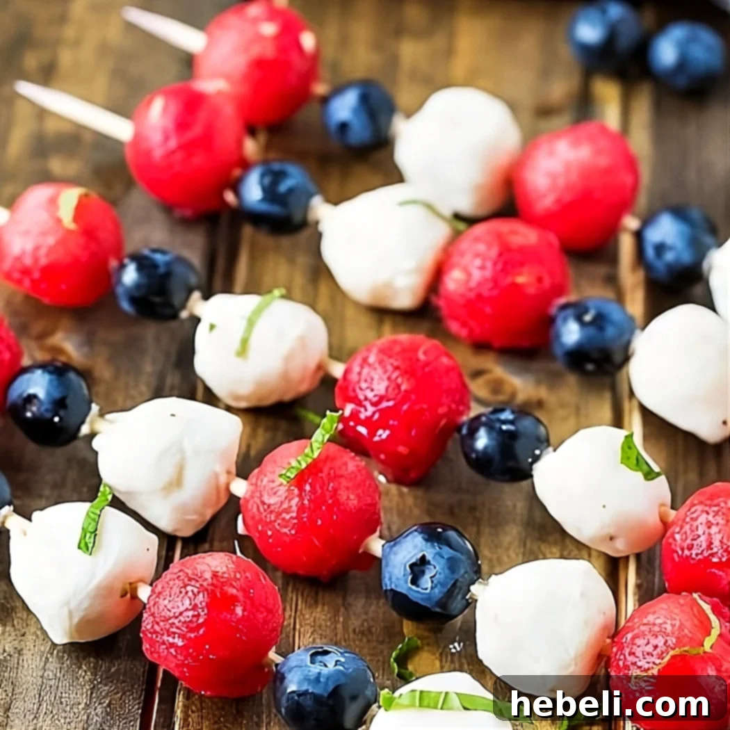 Red White and Blue Fruit Kabobs 2 Colorful Fruit Kabobs featuring red watermelon, white mozzarella, and blue blueberries, perfectly arranged on a picnic table for a festive Fourth of July celebration.