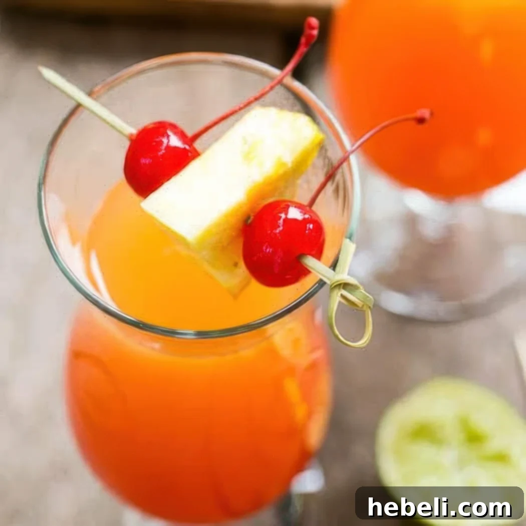 Inverted Aloha 2 A vibrant Pineapple Upside Down Drink, garnished with a pineapple slice and cherry, set in a clear glass.