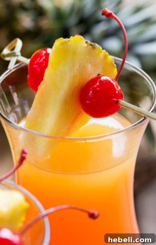 Inverted Aloha 8 A single Pineapple Upside Down Cocktail in a hurricane glass, ready to be enjoyed.