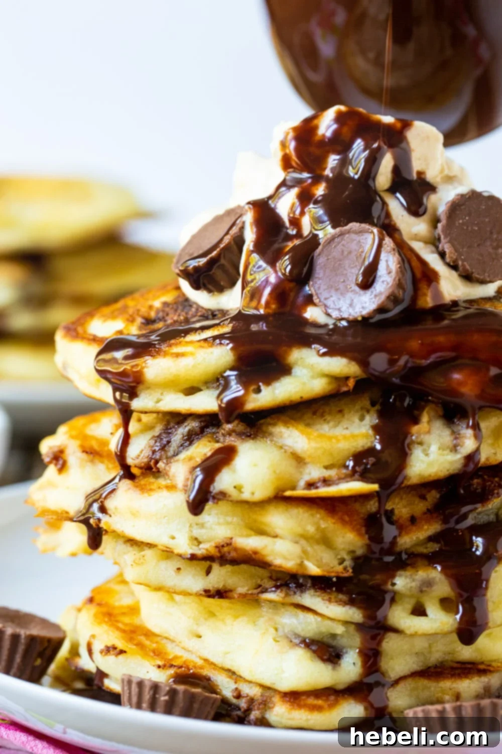 Ultimate Peanut Butter Chocolate Flapjacks 3 A stream of homemade chocolate syrup elegantly flowing down the sides of a tall, tempting stack of Peanut Butter Cup Pancakes.