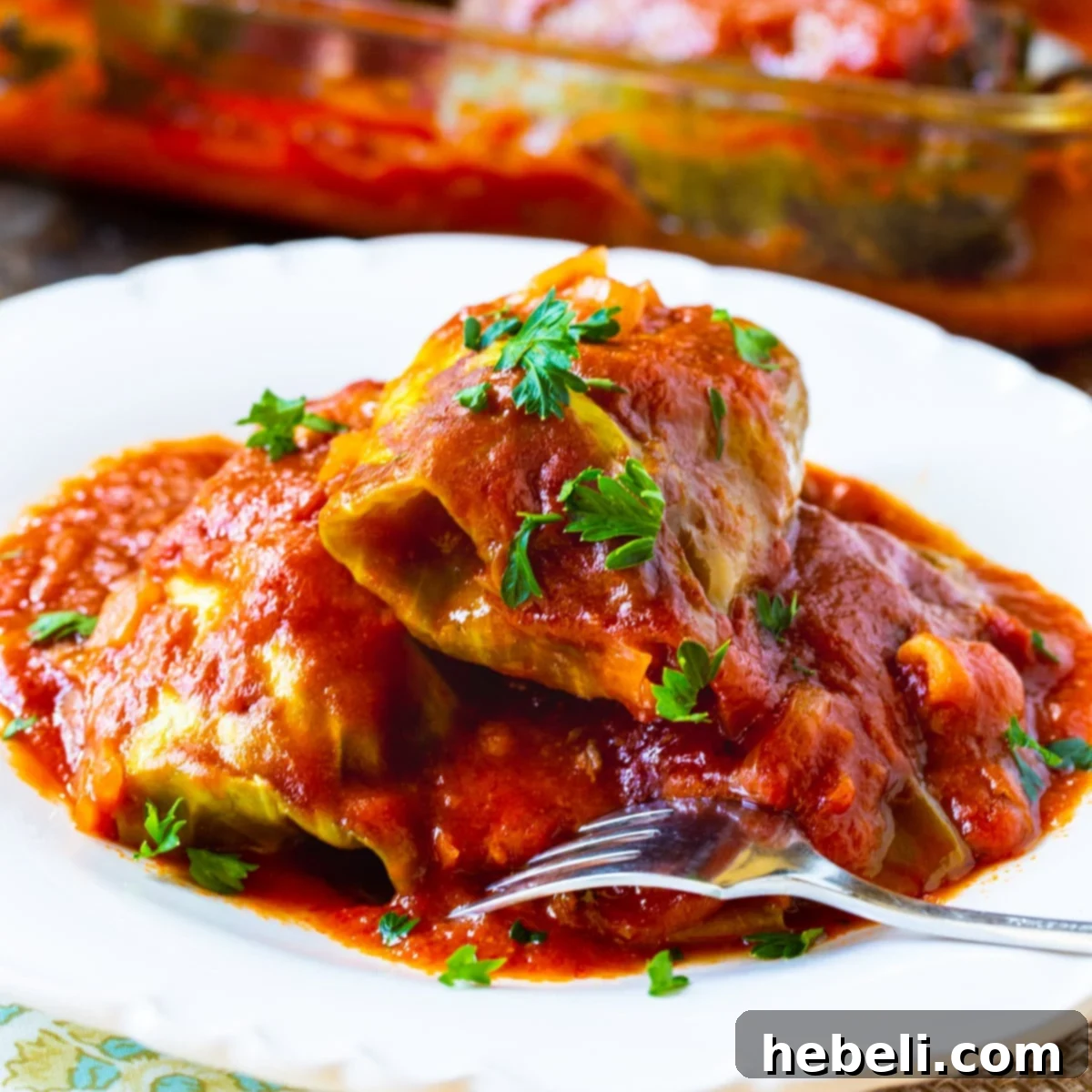 Savory Stuffed Cabbage Rolls 2 Three perfectly rolled and cooked Stuffed Cabbage Rolls on a white plate, garnished with fresh parsley.
