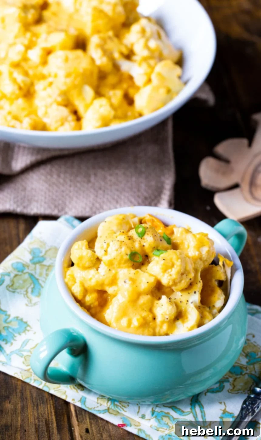 Creamy Slow Cooker Cheesy Cauliflower 4 A large serving bowl of Crock Pot Cauliflower and Cheese with a smaller individual bowl in the foreground, ready to serve.