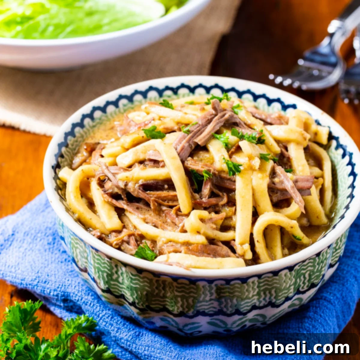 Ultimate Slow-Cooked Beef Noodles 2 A generous bowl of Crock Pot Beef and Noodles, showcasing tender shredded beef and thick egg noodles in a savory broth, perfect for a cozy meal.