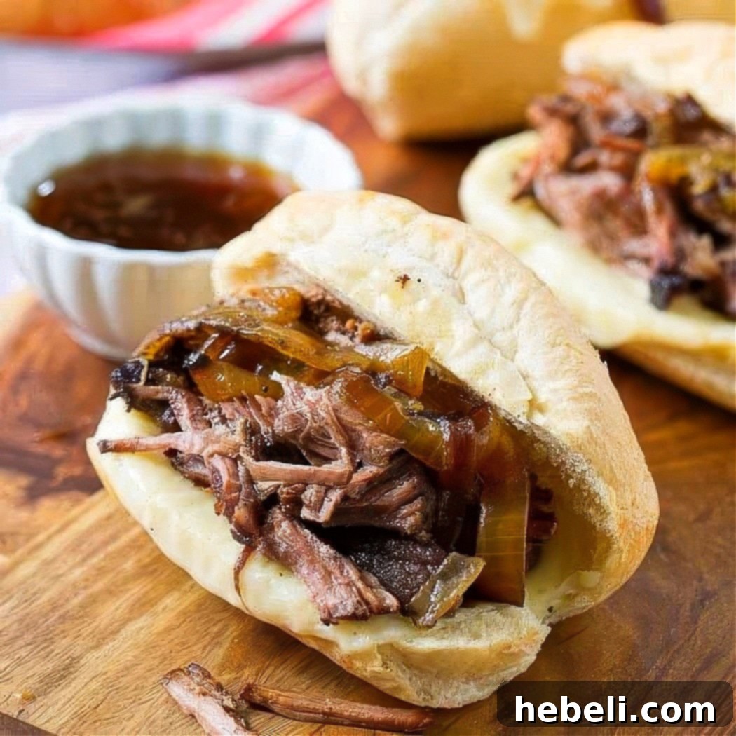 Close-up of a delectable Crockpot French Dip Sandwich with tender beef and melted cheese on a wooden board, ready for dipping.