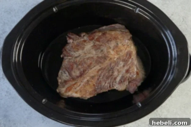 Seared chuck roast transferred to a slow cooker.