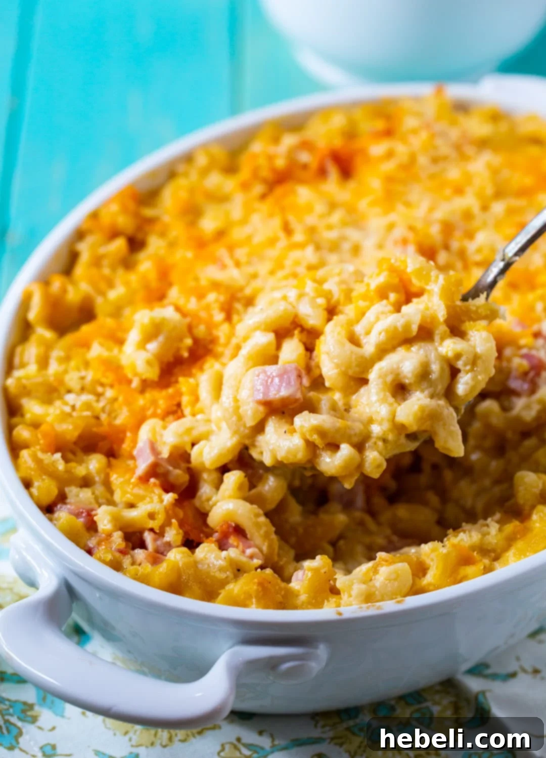 Golden Baked Ham Macaroni 8 Close-up of a spoon scooping up a generous portion of creamy Mac and Cheese with Ham, highlighting its rich texture and savory ingredients.
