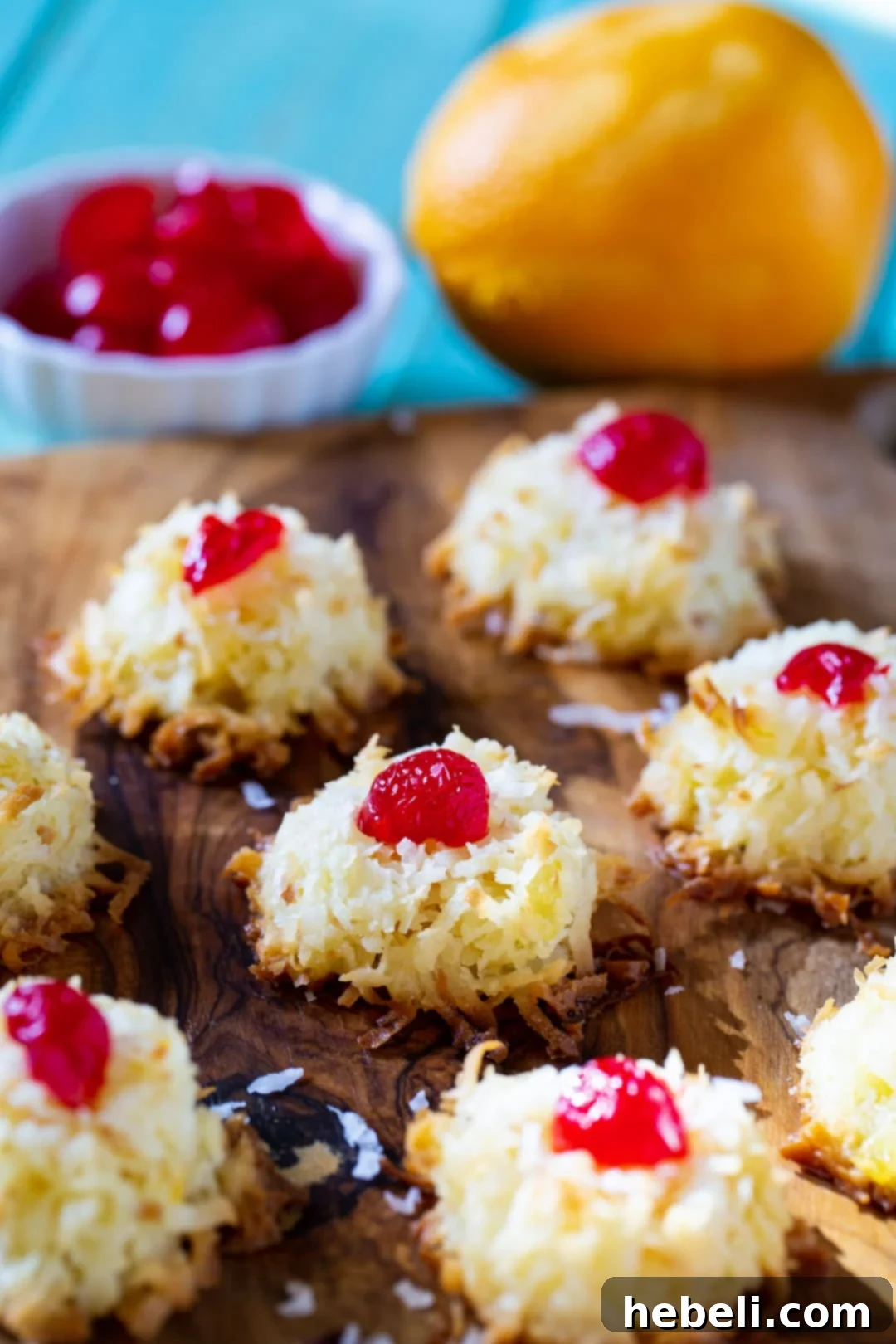 Ambrosia Macaroons arranged on a rustic wood board with a bowl of fresh cherries, highlighting their festive appeal.