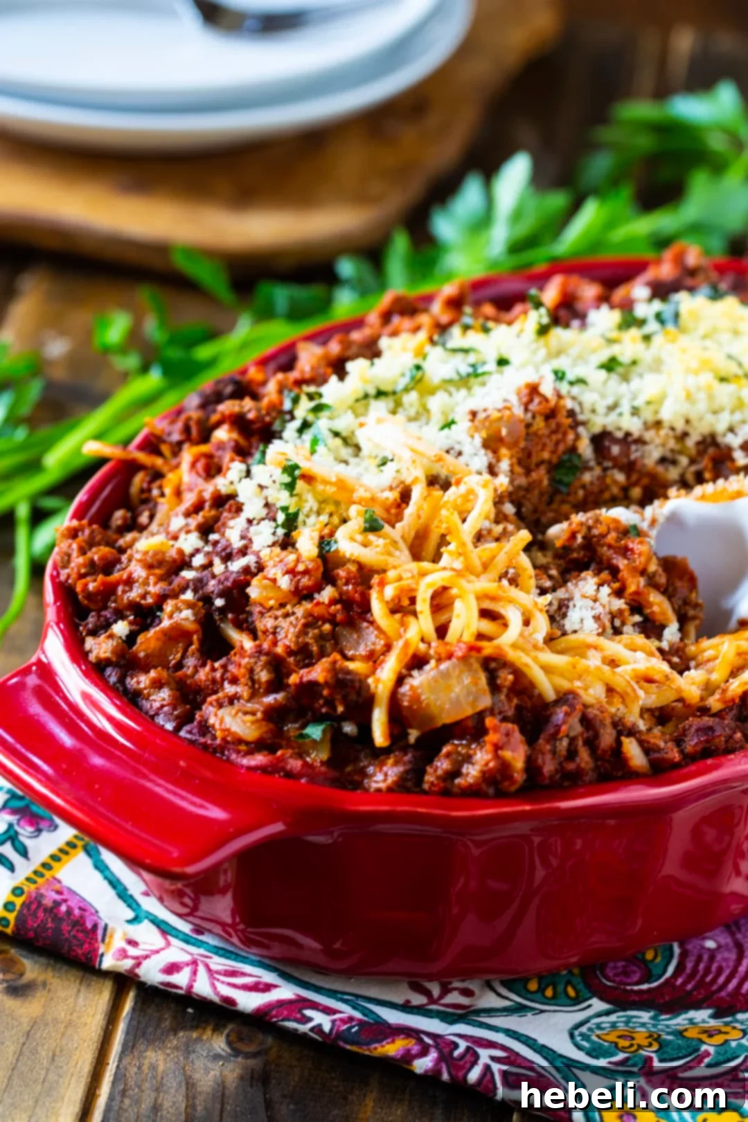 Spoon scooping up a generous portion of Cream Cheese Spaghetti Casserole from the baking dish.