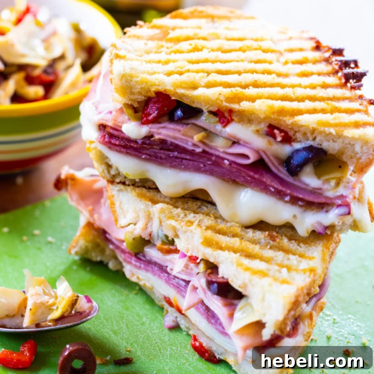 Muffaletta Panini cut in half and stacked, showcasing layers of meat, cheese, and olive salad.