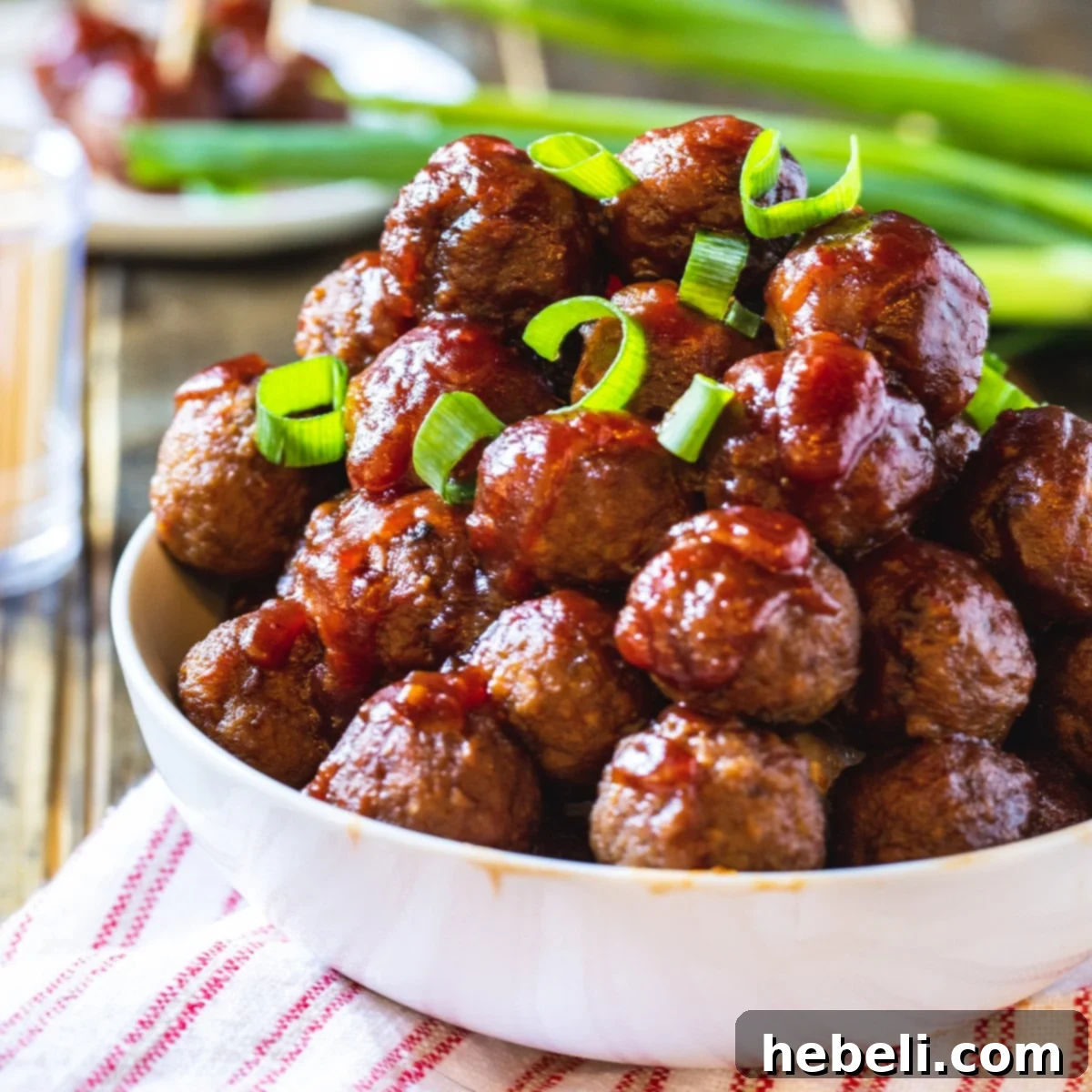 Crock Pot Cranberry Meatballs topped with fresh sliced green onions, ready to be served as an appetizer.