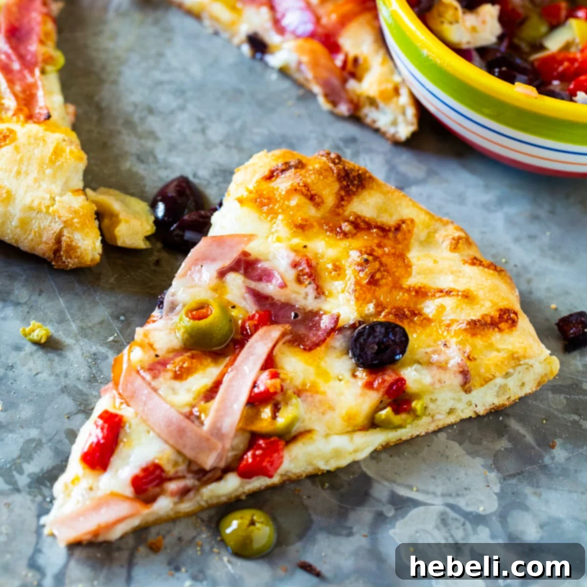 New Orleans Muffaletta Pizza 2 A delectable slice of Muffaletta Pizza, showcasing layers of meats, cheese, and olive salad on a golden crust, ready to be enjoyed.