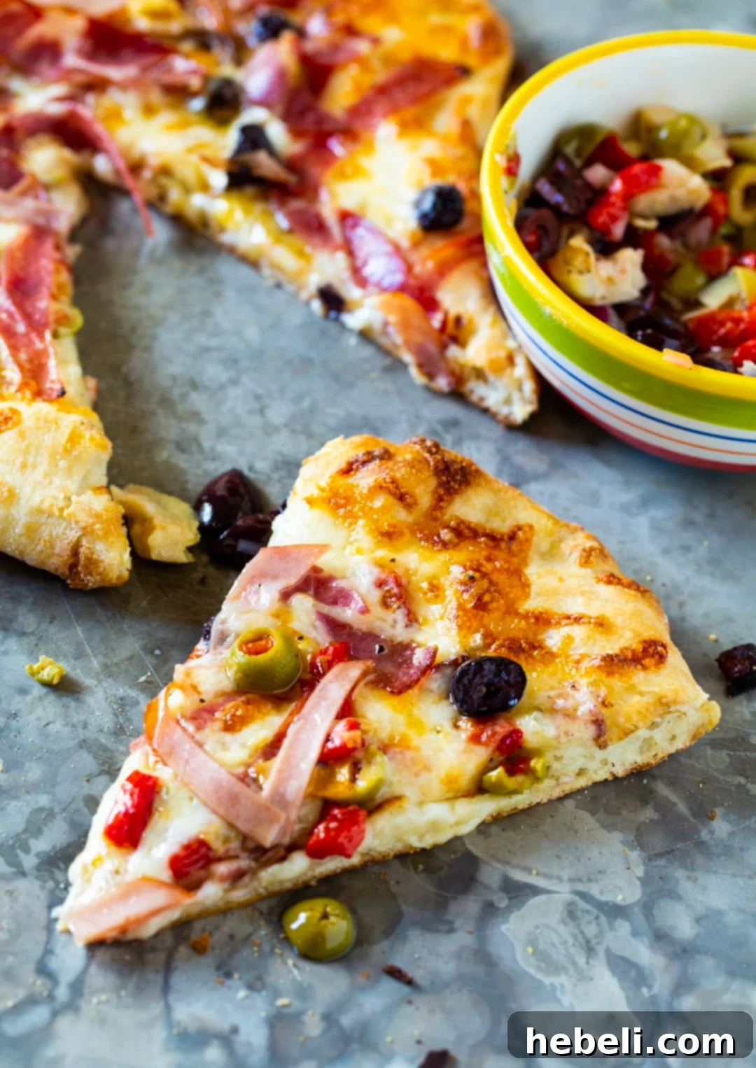 New Orleans Muffaletta Pizza 4 A perfectly baked slice of Muffaletta Pizza, showing the crisp crust, melted cheese, and abundant savory toppings.