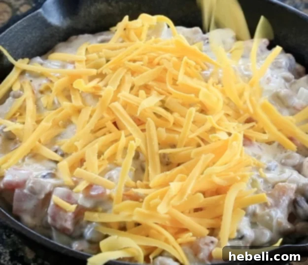 Fiery Black-Eyed Pea Delight 7 The black-eyed pea dip mixture transferred to a baking dish, with shredded cheese sprinkled generously on top, ready for the oven.