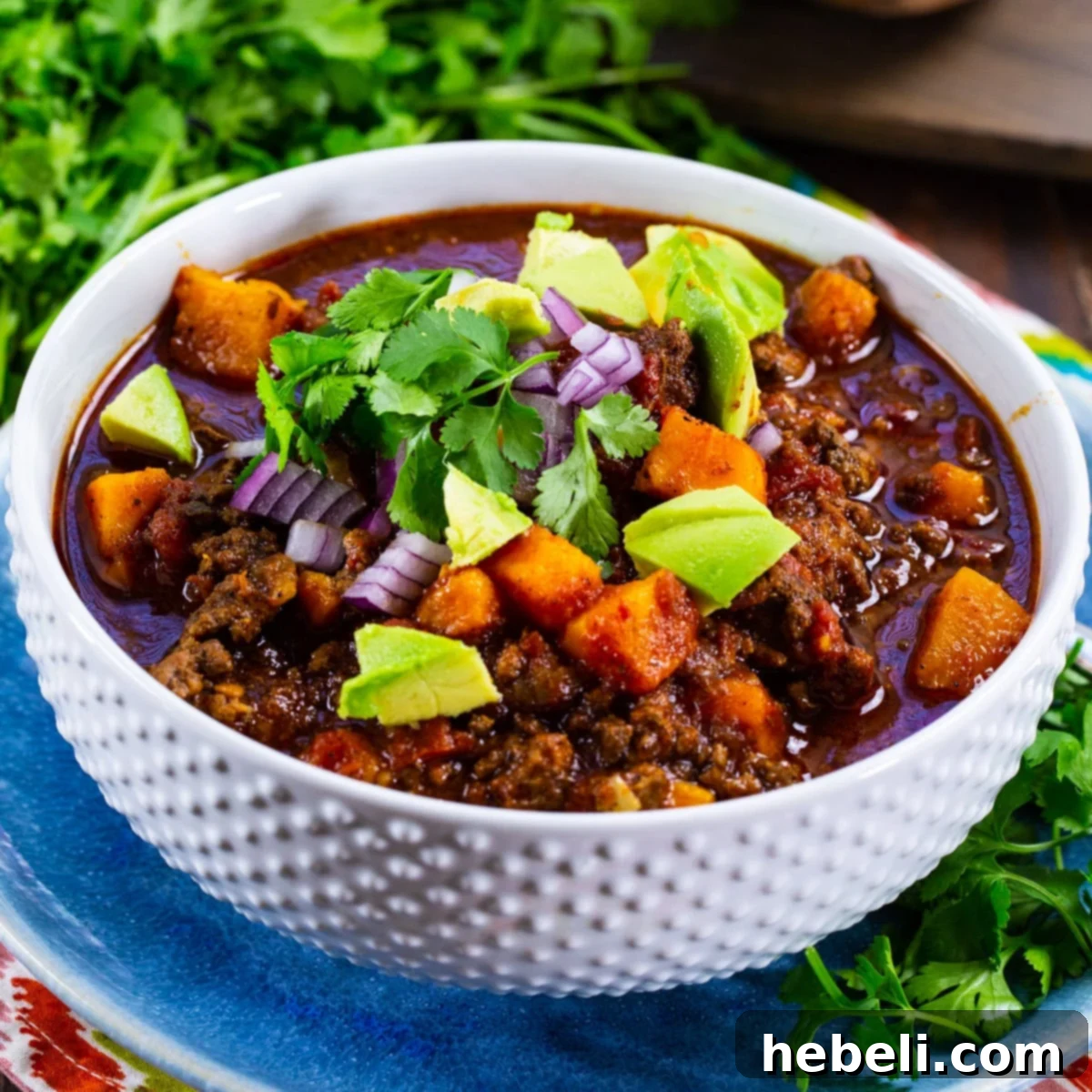A steaming bowl of Slow Cooker Beef and Sweet Potato Chili, garnished for freshness.