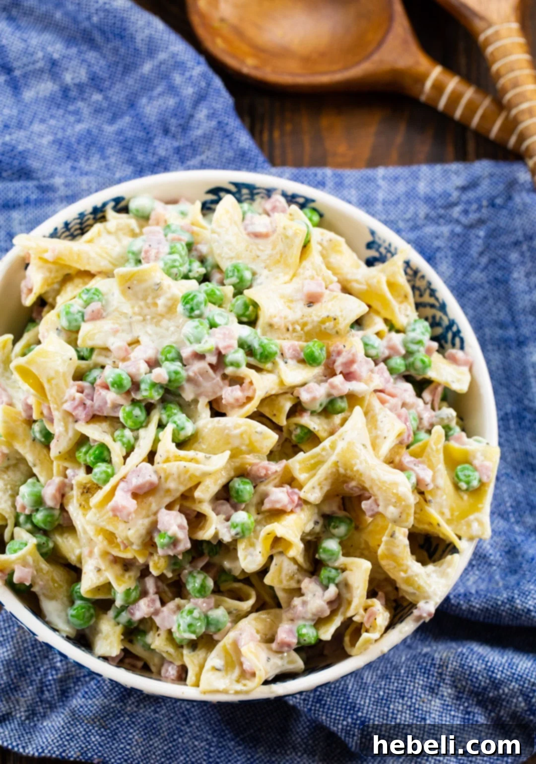 Overhead shot of a bowl of ranch noodles with ham, garnished with fresh herbs.
