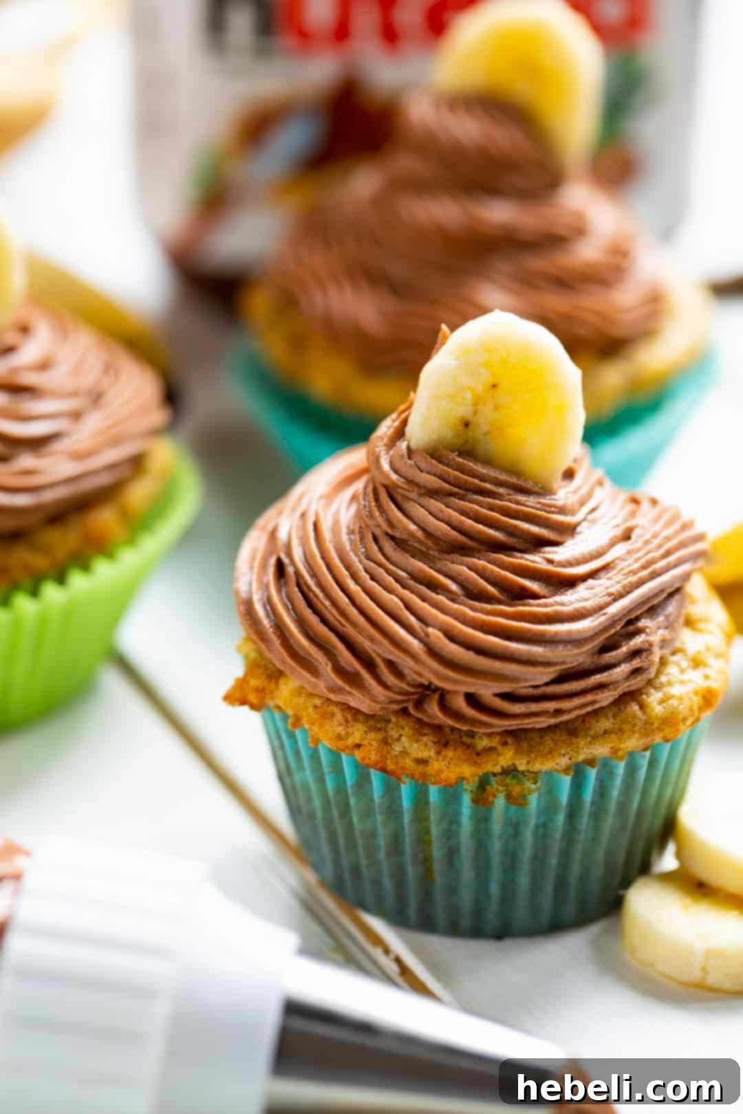 Golden Banana Nutella Delights 3 A freshly baked banana cupcake positioned next to a piping bag filled with smooth Nutella frosting, indicating the next step in decoration.