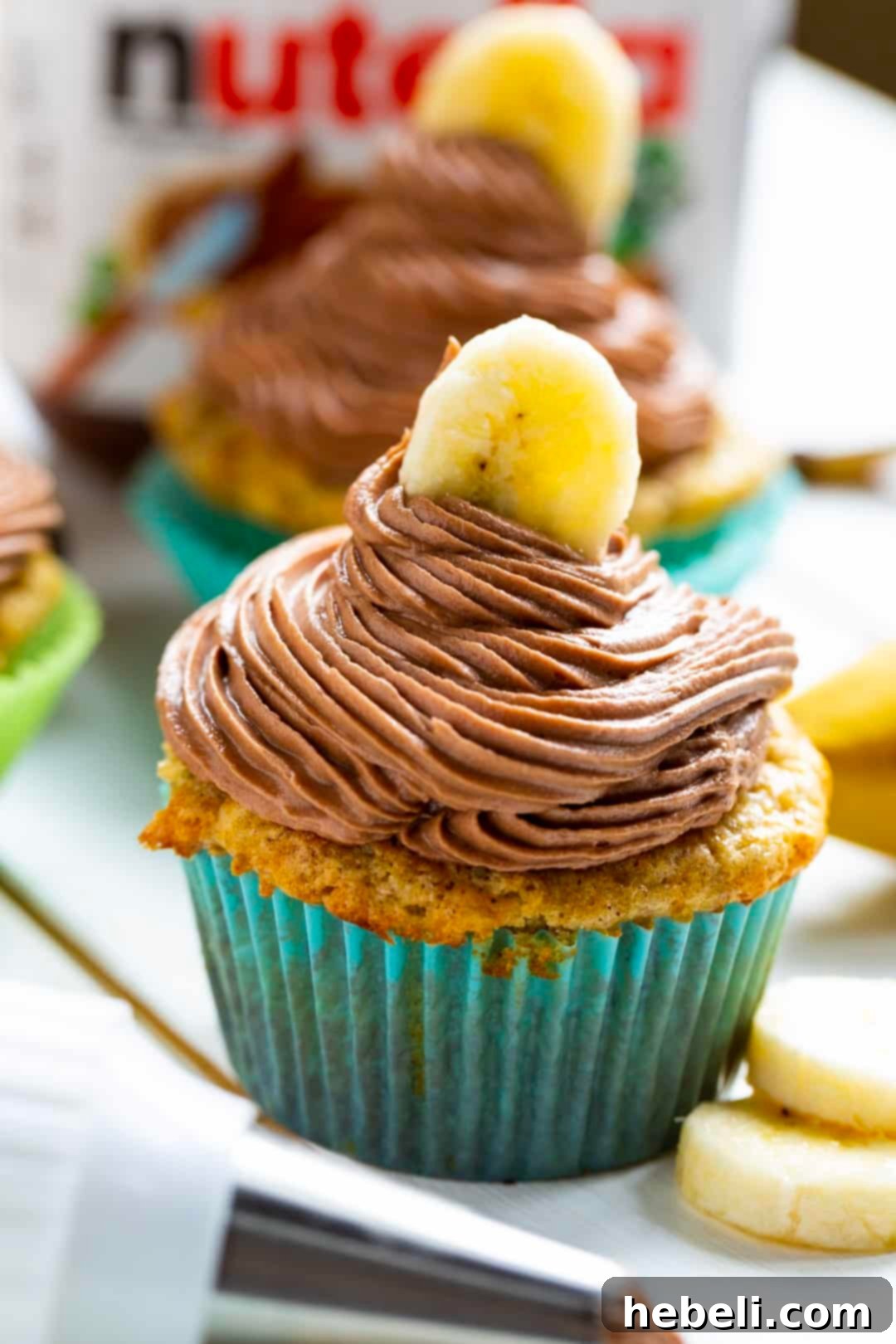 Golden Banana Nutella Delights 4 A close-up view of a Banana Cupcake adorned with a generous swirl of Nutella Frosting and a delicate banana slice garnish, ready to be eaten.