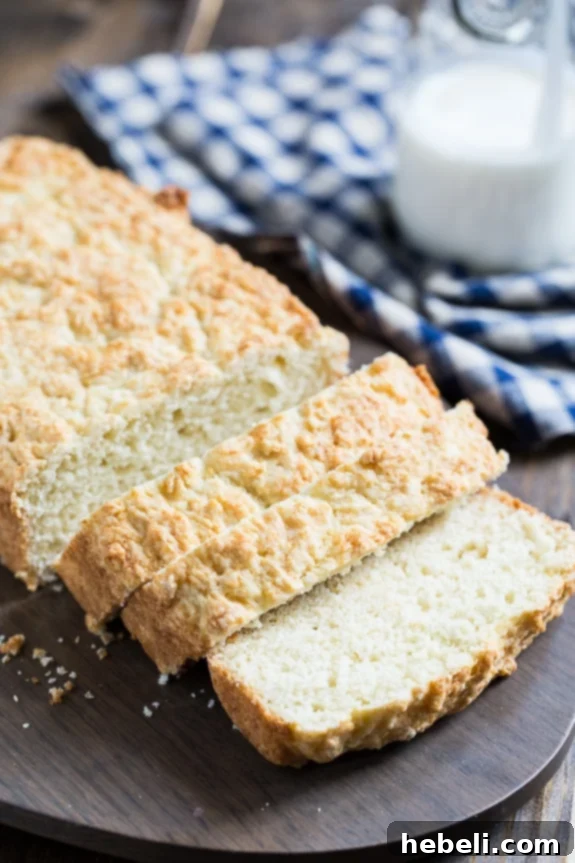 A perfectly sliced piece of Homemade Buttermilk Bread on a wooden board