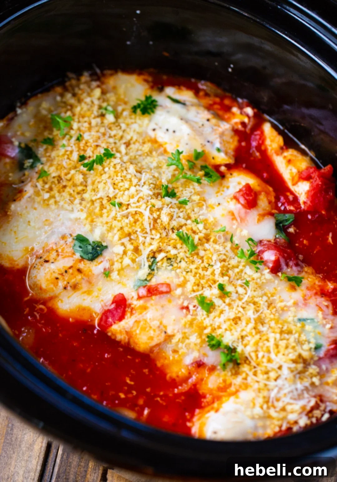 Chicken Parmesan simmering in a slow cooker, before cheese and topping.