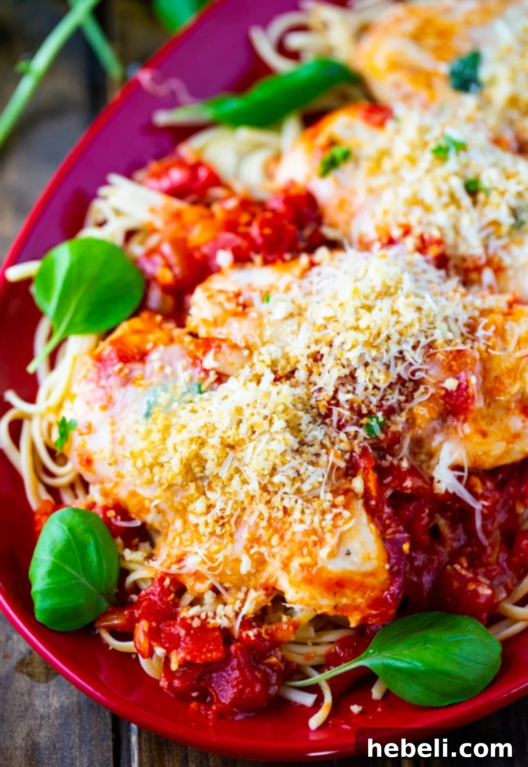 Crock Pot Chicken Parmesan served over pasta on a white plate with fresh basil garnish.