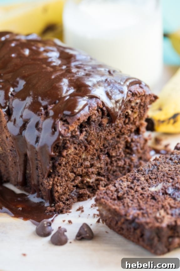 Decadent Triple Chocolate Banana Loaf 5 A close-up view of a slice of Triple Chocolate Banana Bread on a white serving platter, showing off its moist texture and rich chocolate.