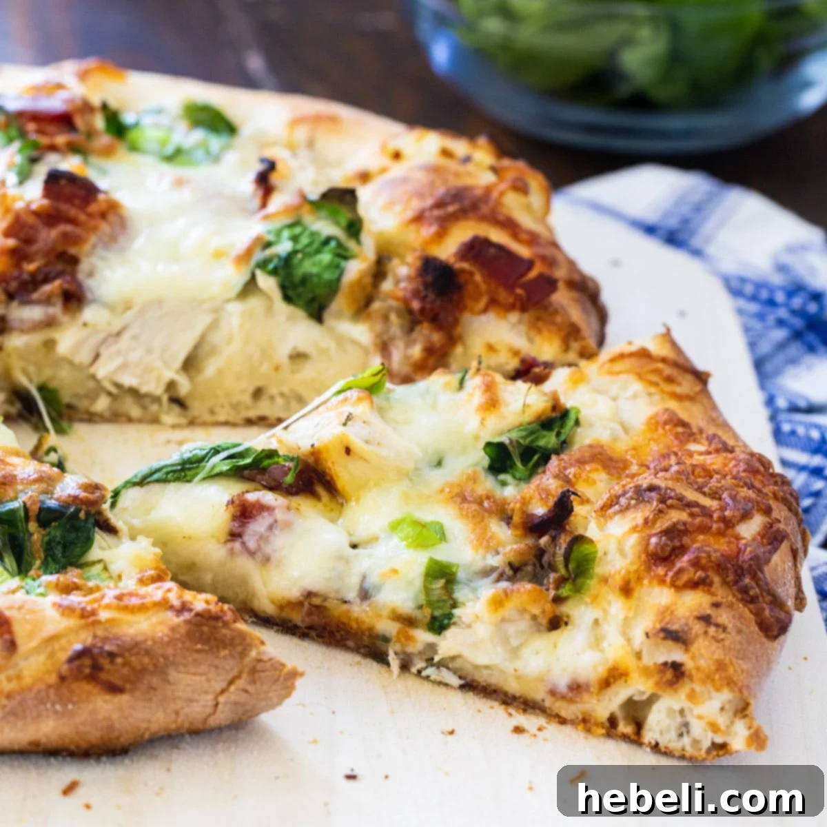 Chicken Alfredo Pizza with a slice expertly cut, showcasing its delicious layers and golden crust.