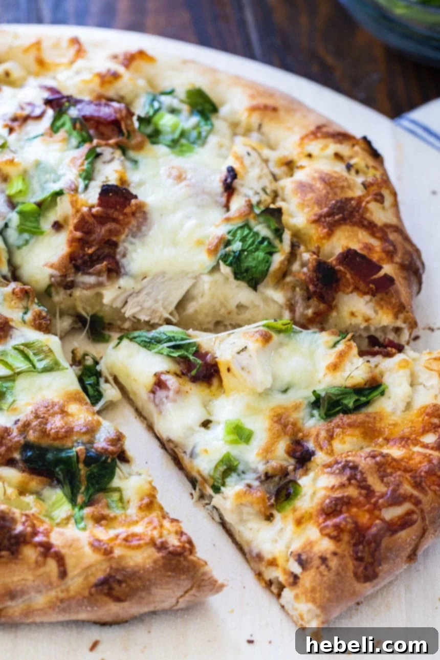 Close-up detailed view of a freshly baked Chicken Alfredo Pizza, showing the perfectly melted cheese and rich toppings.