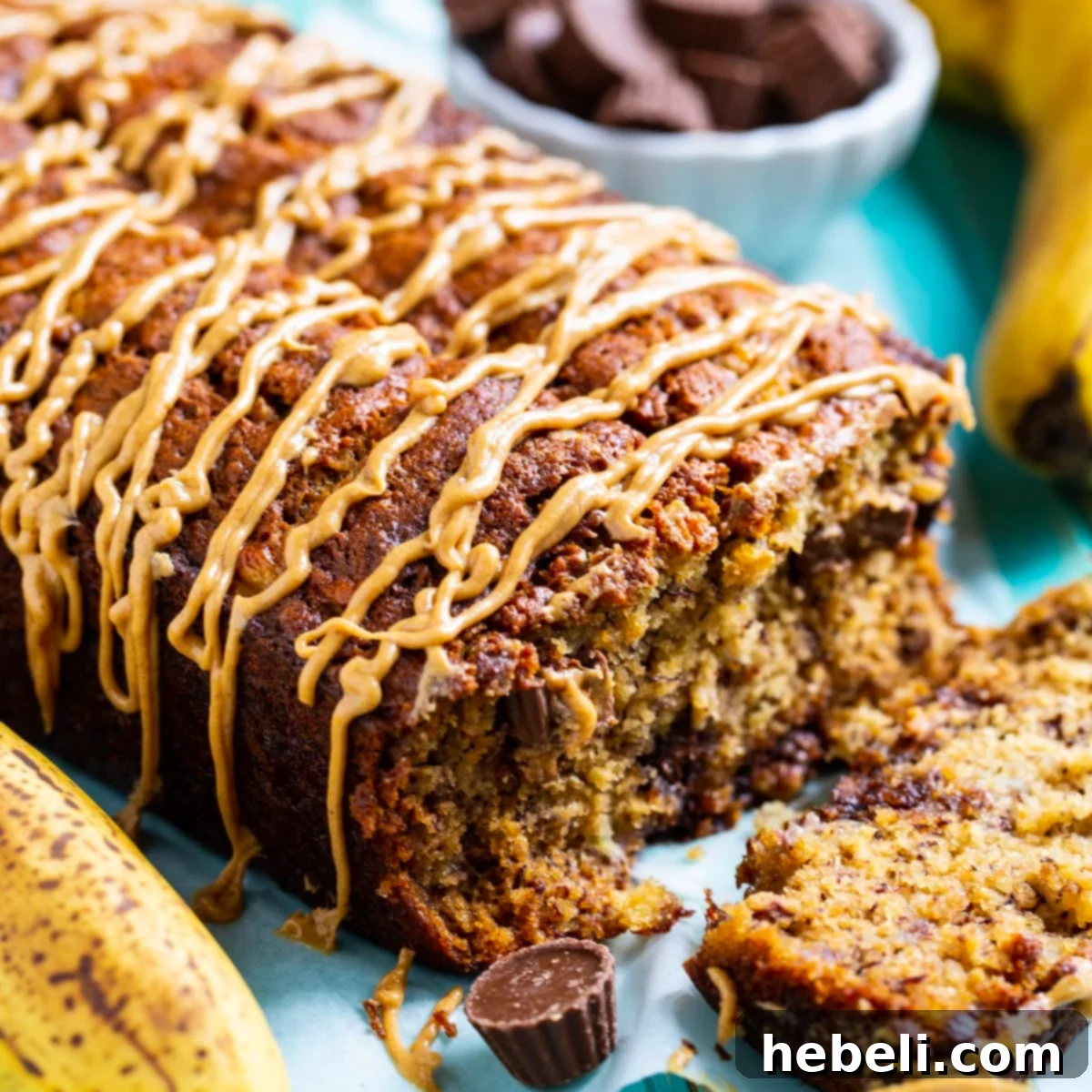 A glorious slice of Peanut Butter Cup Banana Bread, revealing melted chocolate and peanut butter pockets, topped with a creamy peanut butter glaze, ready to be enjoyed.