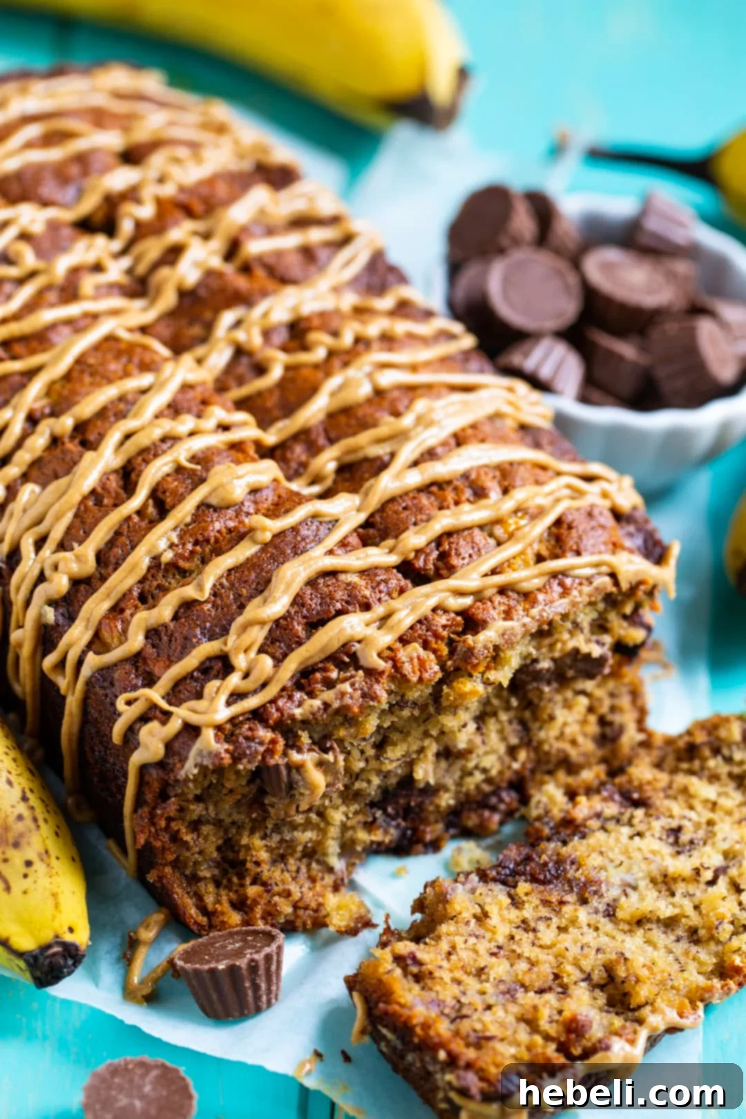 A freshly baked loaf of Peanut Butter Cup Banana Bread, generously drizzled with a smooth and glossy peanut butter glaze, inviting you to take a bite.