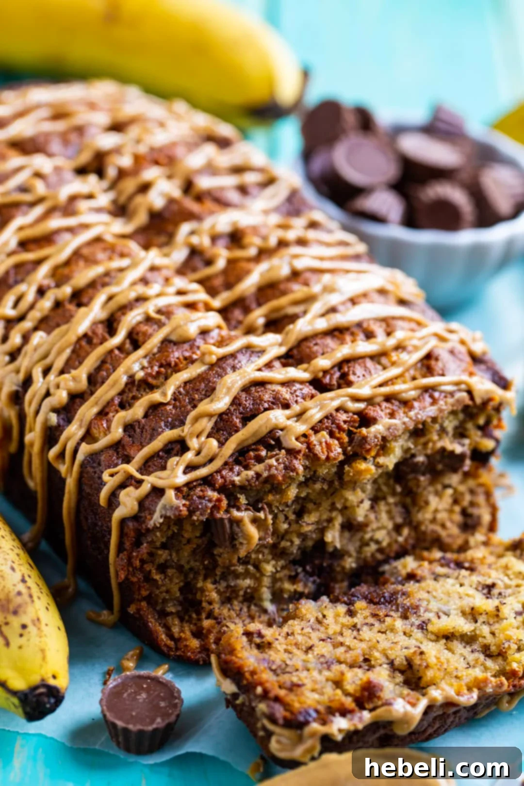A freshly cut slice of Peanut Butter Cup Banana Bread on a rustic cutting board, showcasing the moist interior and the delightful melted peanut butter cups within.