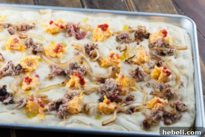 Southern Comfort Focaccia 5 Focaccia dough before baking, showing dimples and toppings.