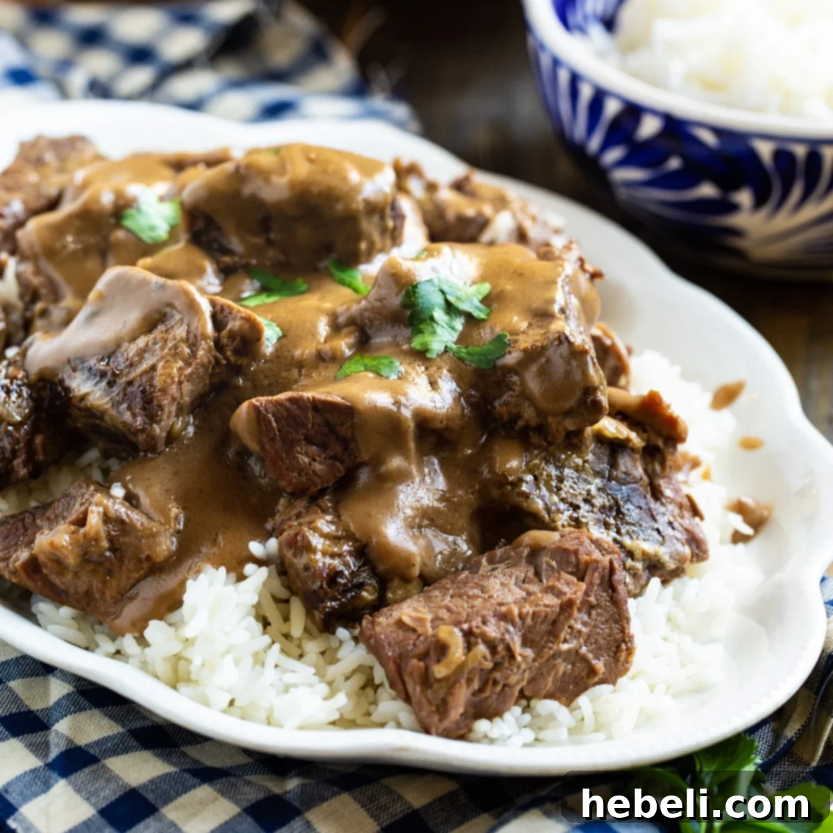 Crock Pot Beef Tips with Gravy served over white rice, garnished with fresh parsley.