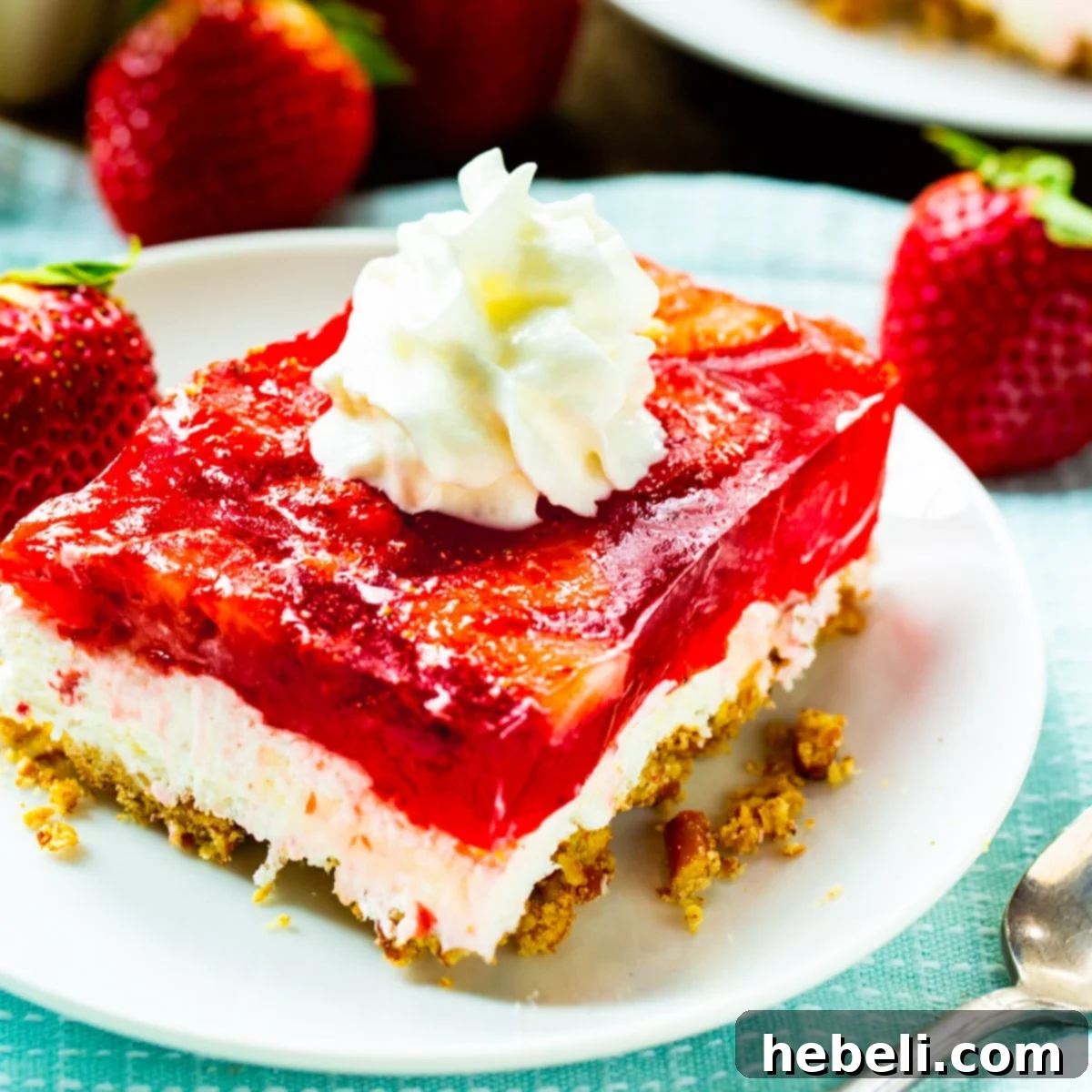 Slice of Strawberry Pretzel Salad on a plate, showcasing its three distinct layers: pretzel crust, cream cheese, and strawberry jello.