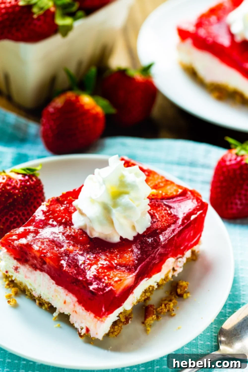 Two generous slices of Strawberry Pretzel Salad presented on a white plate, elegantly garnished with whole fresh strawberries around it.