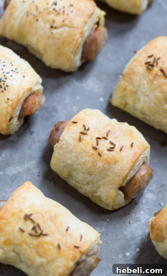Close-up of baked German-Style Pigs in a Blanket, showing the flaky pastry, bratwurst, mustard, and sauerkraut filling