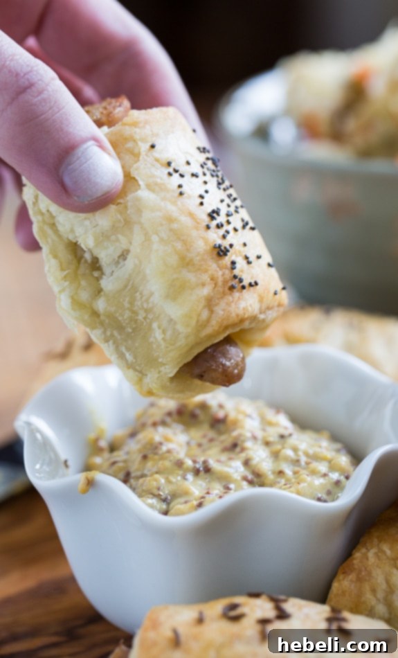 A selection of perfectly baked German-Style Pigs in a Blanket served with a small bowl of mustard