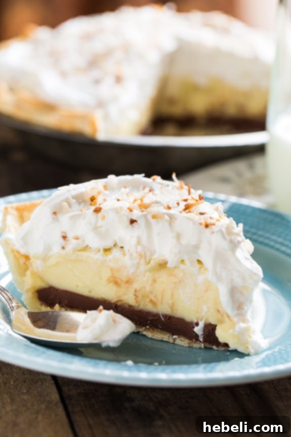 A stunning Black Bottom Coconut Cream Pie with a fluffy whipped cream topping and crunchy toasted coconut flakes, ready to be enjoyed.