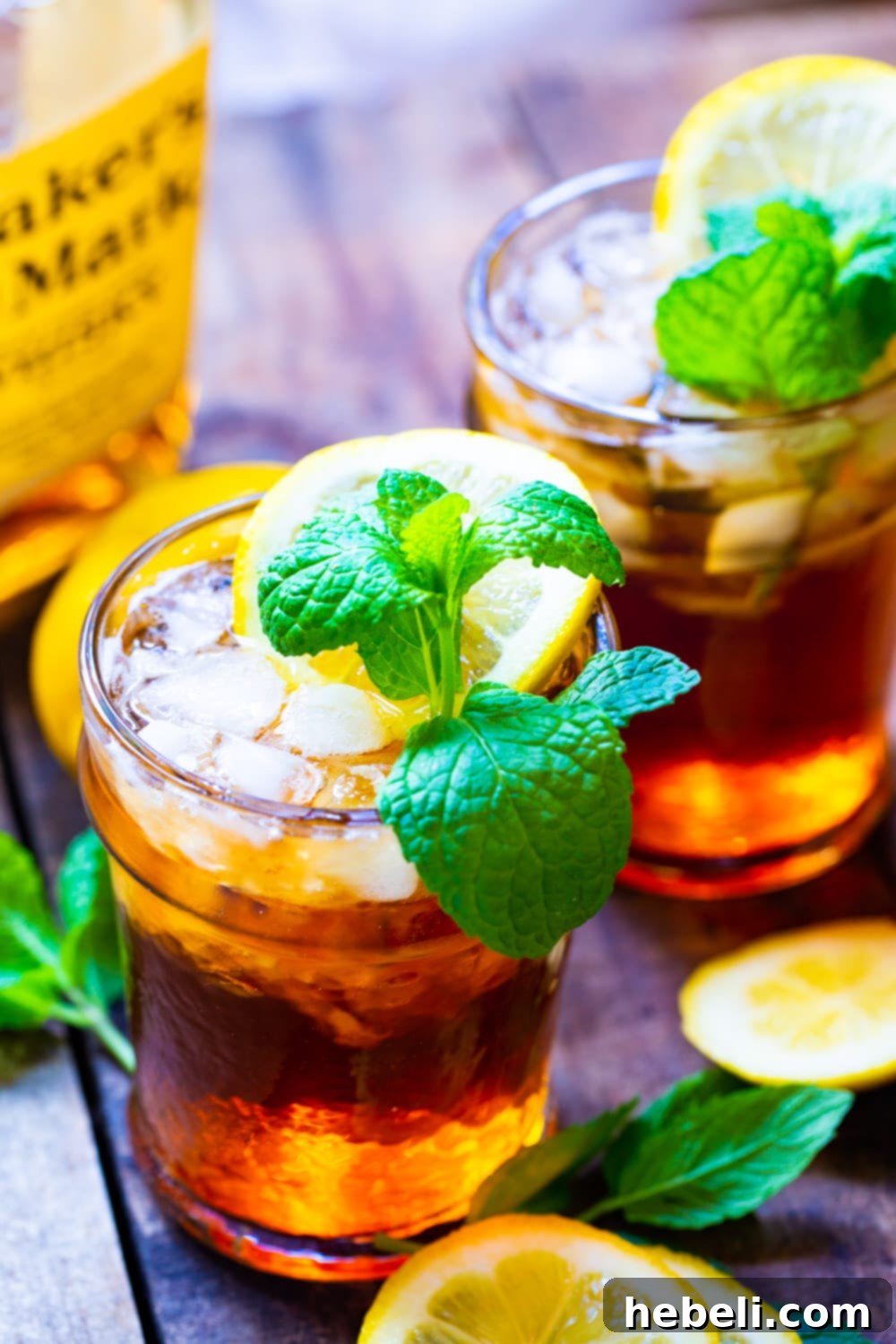 Two vibrant Sweet Tea Mint Juleps garnished with lemon slices and mint sprigs in elegant glasses.